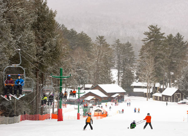 Scene of a ski hill, people skiing and riding the lift